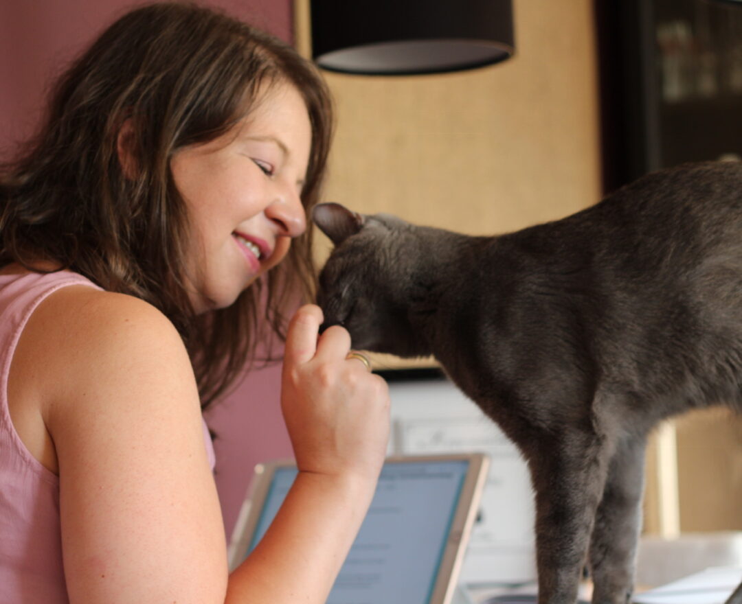 Katrin Knispel im Gespräch am Laptop, eine Katze schmiegt sich an sie